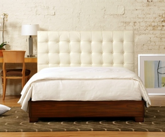 A rich stained wooden bed with a white leather tufted headboard looks chic and refined and will make a statement in a mid century modern room