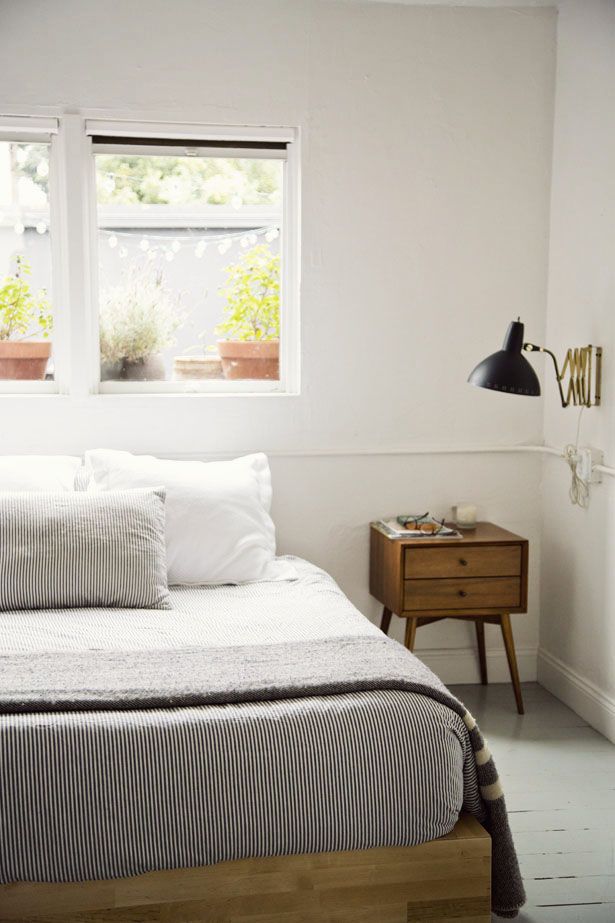 A simple and laconic light stained wooden bed for a stylish neutral mid century modern bedroom