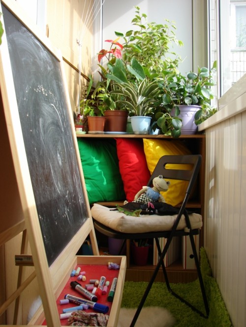 a small balcony with potted plants and a chair plus a kid's easel to inspire your child to be creative