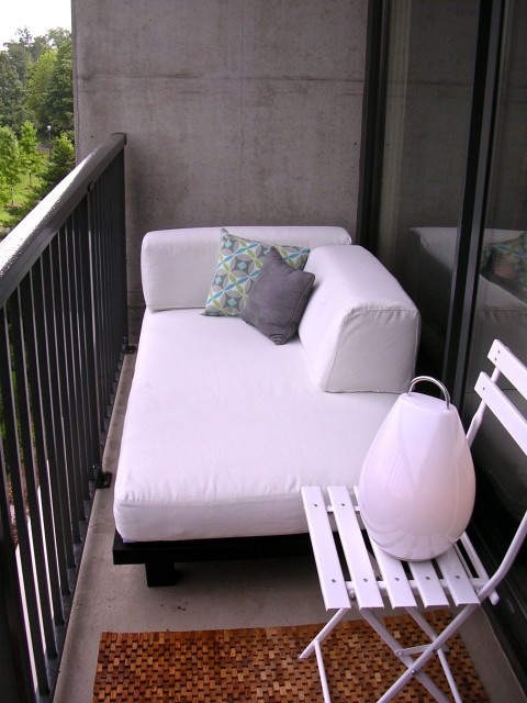 A small balcony finished off with elegant modern furniture   a sofa and a folding chair   is a great nook to spend some time in