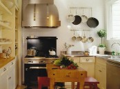 a warm-colored rustic kitchen wiht metal countertops, built-in cabinets and shelves, a large hood and a small table with red stools