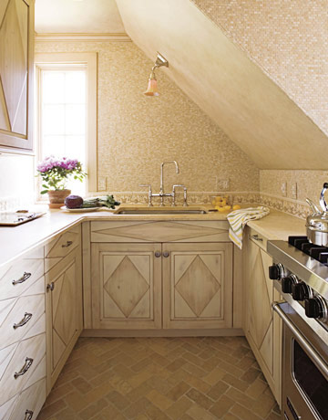 a small French inspired kitchen with elegant geometric cabinets, mosaic tiles and a ceiling lamp