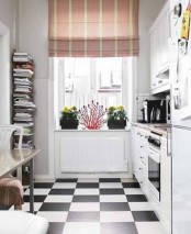 a small white kitchen with checked floors, butcherblock countertops, a bright striped curtain and a stand with books is cozy