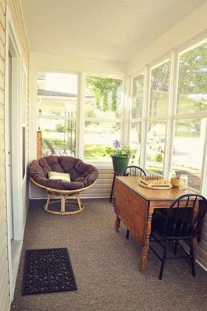 a sunroom dining/playing space with a foldable table, some chairs and an upholstered round chair