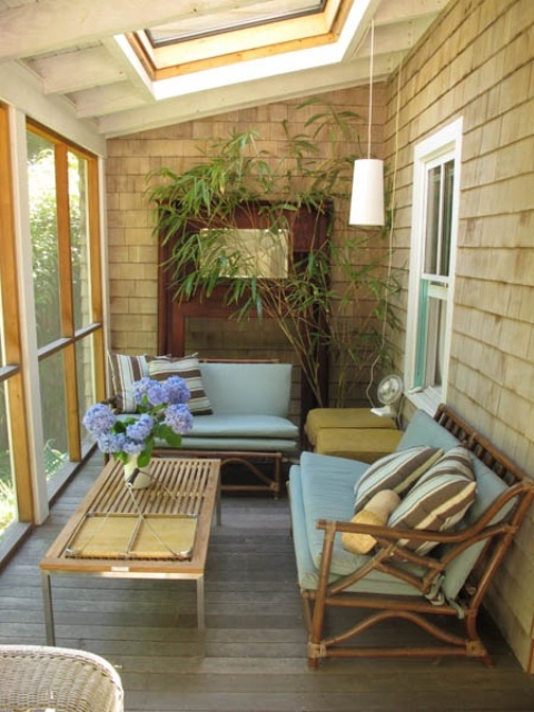a mid-century modern sunroom done in sandy shades, with rattan chairs, pendant lamps and potted greenery