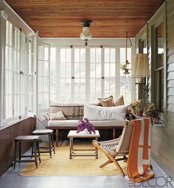 A retro inspired sunroom with wooden and wicker furniture, lamps and lights and touches of color