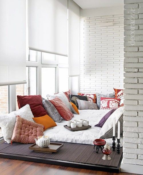 a chic contemporary sunroom nook with a sitting place right on the floor and lots of pillows for a boho feel