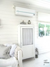 a stylish and small whitewashed cabinet with a glass door but with curtains is a cool idea for a Scandinavian interior