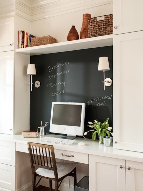 a rustic home office nook with built-in white cabinets, a small working space with a chalkboard for leaving notes, a PC and a simple chair