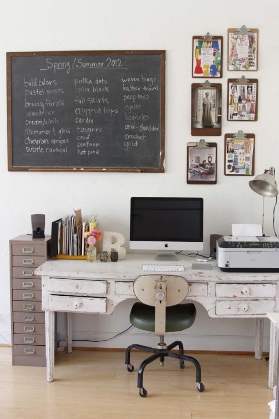 a vintage industrial home office with a white vintage desk, a neutral chair, a metal file unit, a large chalkboard and a gallery wall with photos