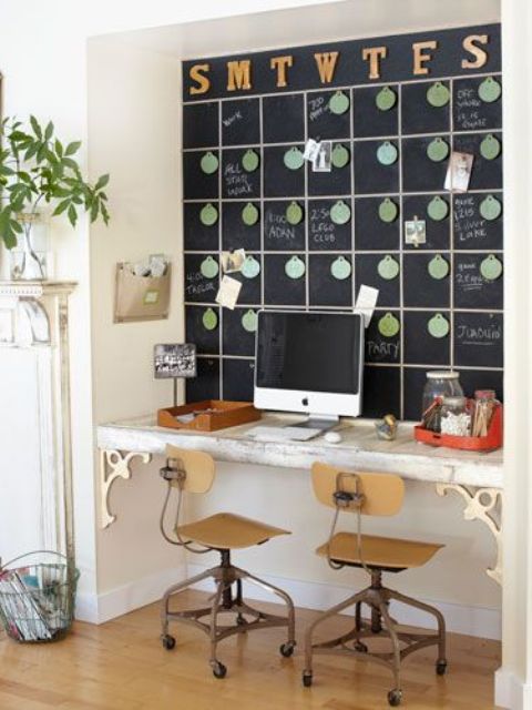 An eclectic working nook with a chalkboard schedule that is used for planning, a built in vintage desk and industrial chair and potted greenery