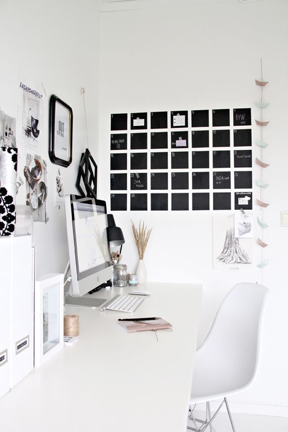 A Scandinavian home office with a white desk and a chair, a gallery wall and a chalkboard schedule that helps planning each day