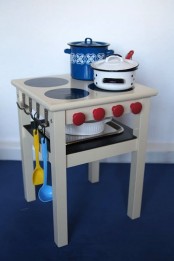 a bold kids’ kitchen made of an IKEA Oddvar stool with hooks, knobs and trays
