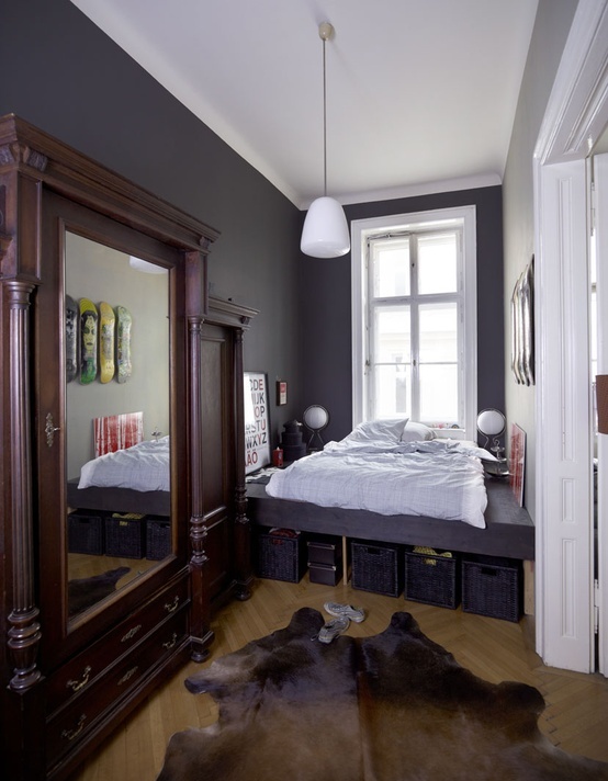 A small eclectic bedroom with graphite grey walls, a built in bed with storage and wardrobes with mirror doors
