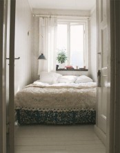 a tiny neutral bedroom with printed wallpaper walls, neutral bedding and wall sconces
