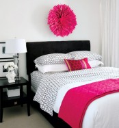 a neutral bedroom with a black bed and nightstand, bright fuchsia touches and chic artworks