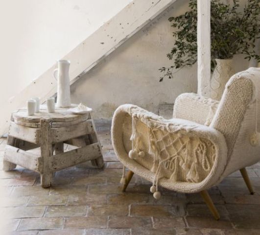 A mid century modern chair with a white crochet cover and tassels is a lovely idea that will cozy you up
