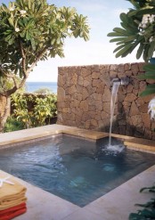 a plunge pool with a waterfall, a stone wall and tiles is a cool idea to relax after a hard and hot day