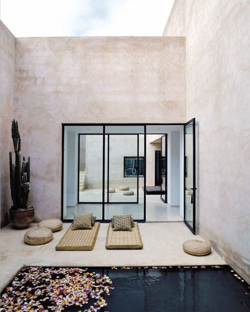 a Moroccan style backyard with loungers, jute ottomans, a plunge pool and a potted cactus