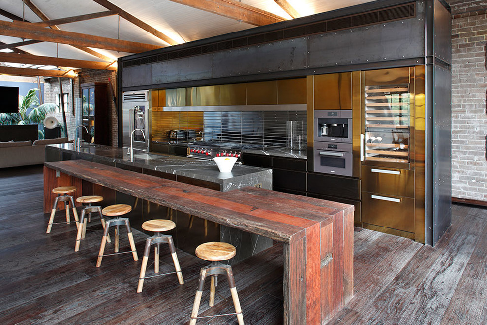 Spacious industrial single wall eat in kitchen located in an old factory building with interesting metallic backsplash