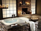 a vintage bathroom clad with faux stone, with a tub clad with it, too, a fireplace, lots of candles is a real relaxation sanctuary that you’ll never want to leave