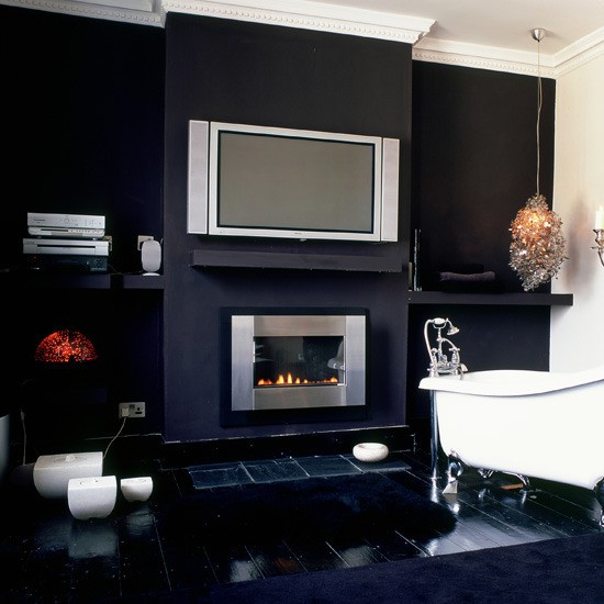 a modern dark bathroom with a TV, a built-in fireplace, a clawfoot bathtub, candles, a pendant lamp is amazing