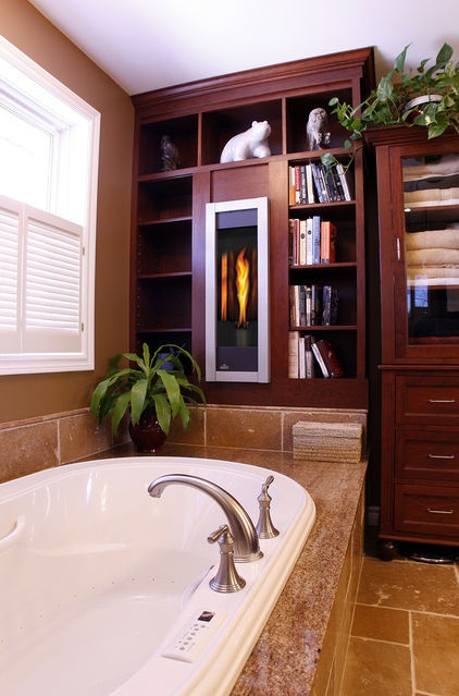 A dark stained storage unit with open shelves and cabinets, a bathtub clad with tan tiles and some greenery to refresh the space