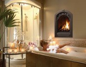 a refined bathroom with a lit up shower, a built-in fireplace, a bathtub clad with large scale tiles and a glass table with candles