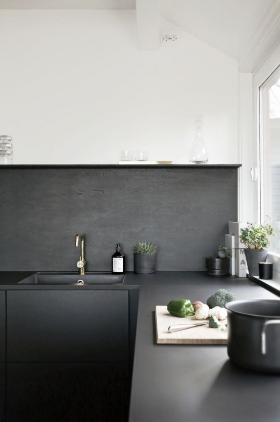 a Scandinavian kitchen with black cabinets, only lower ones, and color block walls - white ones with a black backsplash