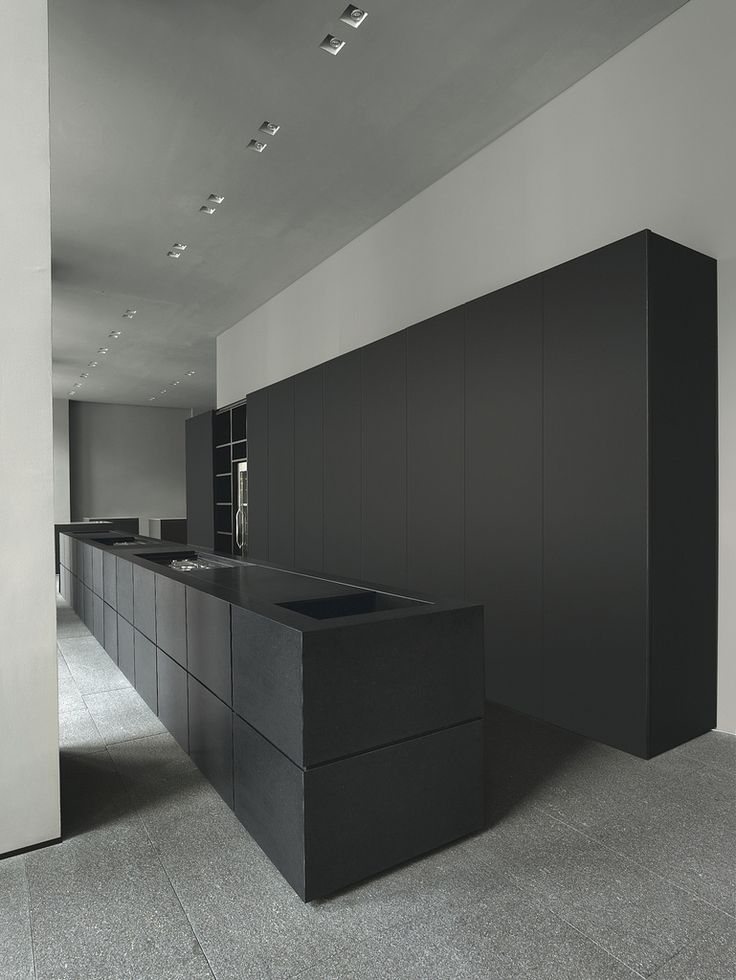 An ultra minimalist black and grey kitchen with matte cabinets and a kitchen island, all the appliances hidden for an ultra minimal look