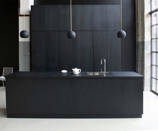 a minimalist matte black kitchen with sleek cabinets, a large kitchen island, pendant lamps and a white floor and a glazed wall for a fresher look