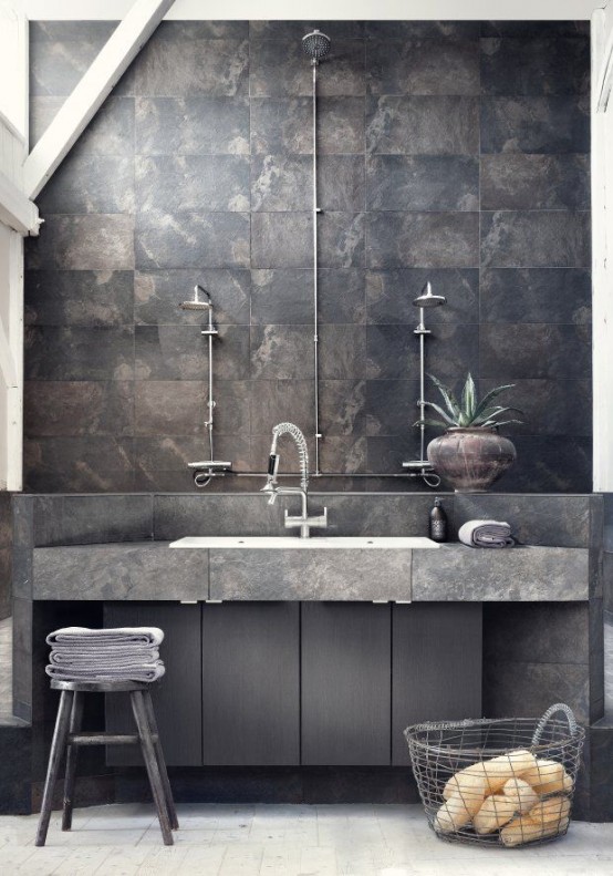 a minimalist industrial bathroom done with rusty tiles, concrete and sleke wooden surfaces, exposed pipes and wooden stools