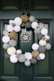 a wreath made of yarn balls in neutral shades, with wooden snowflakes and a rhinestone snowflake pendant for cute winter decor