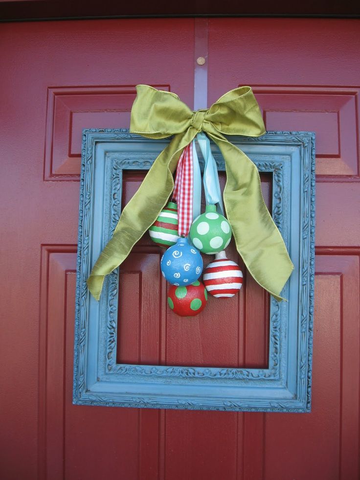 A front door Christmas wreath made of a blue frame with colorful ornaments and a green silk bow is a whimsy and cool idea