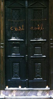 lots of candles in glasses and letters placed on the doors compose a simple and stylish decoration for the front door