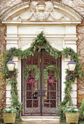 elegant natural Christmas styling with an evergreen garland that frames the entrance, evergreen wreaths with purple bows