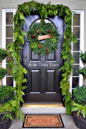 Christmas front door styling with an evergreen garland, a Christmas wreath of greenery, berries and pinecones
