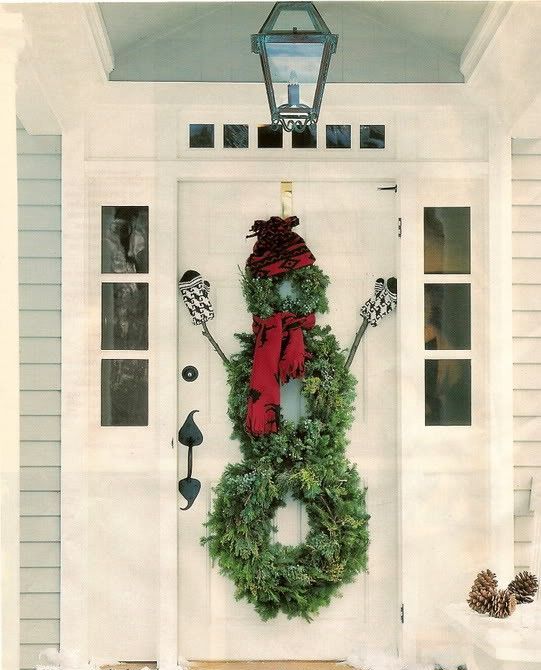 a snowman front door decoration of evergreen wreaths, a red scarf and beanie, sticks and mittens is a fun idea