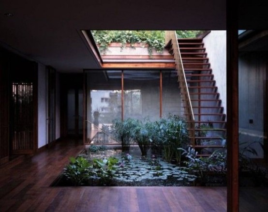 an indoor courtyard with a pond with lots of plants and a skylight over it for a fresh and modern look