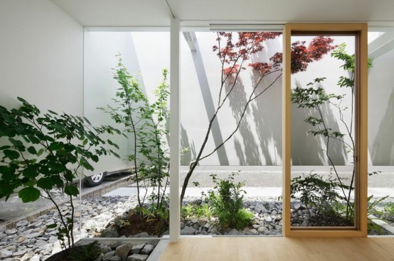 a stylish skylit indoor courtyard with pebbles and rocks and some plants growing here is a cool idea