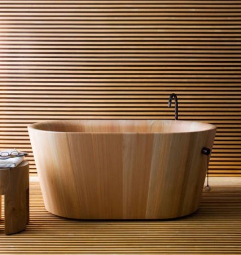 A neutral minimalist bathroom fully clad with light stained wooden slabs, a wooden bathtub and a matching stool is very zen like