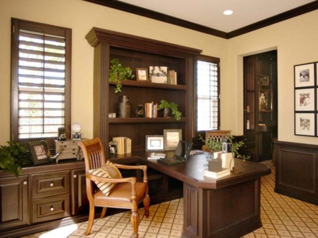 A vintage inspired sandy and dark chocolate home office with stylish furniture, an amber leather chair and potted greenery
