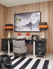 a bright home office with a wood statement wall, a black desk and a striped rug plus table lamps with bright accents