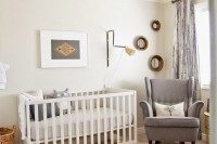 a neutral rustic-inspired nursery with tan walls, a wood grain ceiling, layered rugs, a grey rocker chair and a leather pouf