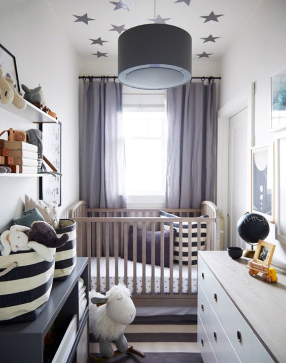 a grey and white nursery with black, white and stained furniture, printed bedding, grey curtains, a star accented ceiling and wall mounted shelves