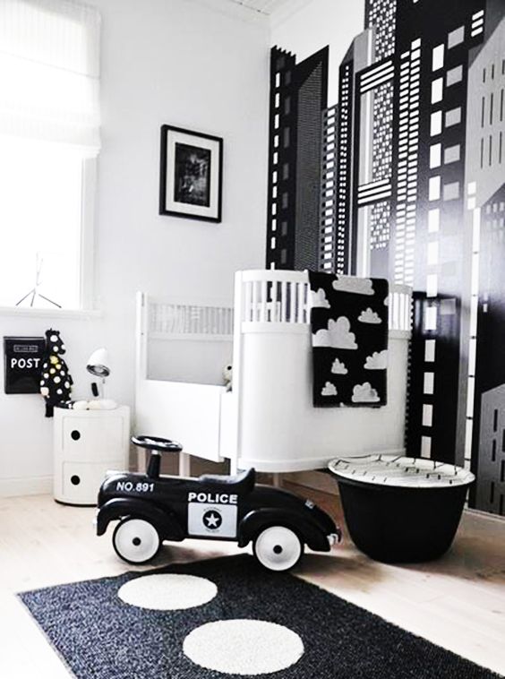 a catchy black and white nursery with an accent wall, a white crib and black and white bedding, a black rug and some black and white toys
