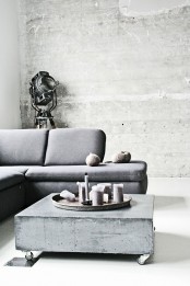 concrete walls echo with a concrete coffee table with casters, and a vintage floor lamp helps creating an industrial feel