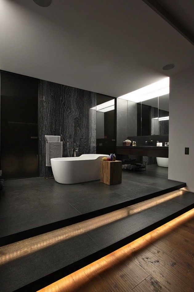 A minimalist moody bathroom with dark walls, a black floor, built in lights, a stone accent walls, white appliances and a dark floating vanity