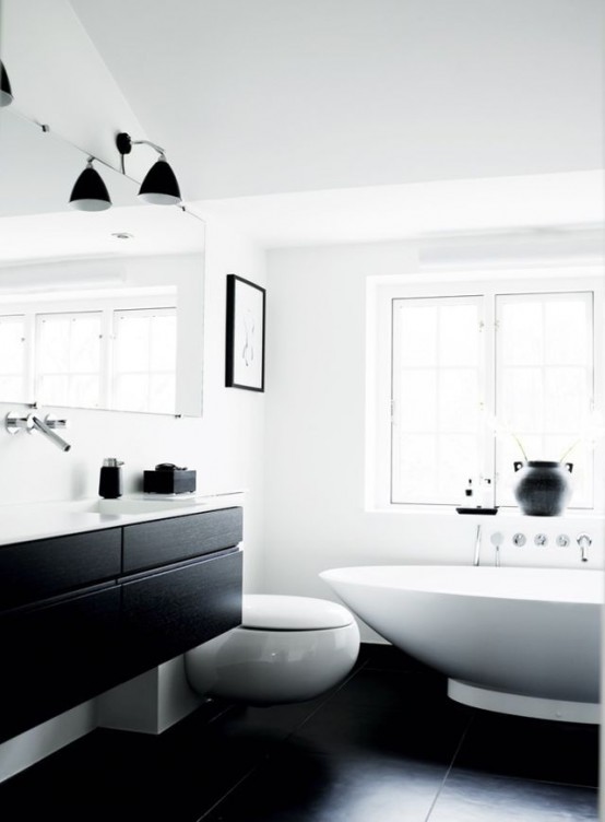 a minimalist contrasting bathroom with white walls, a black floor, a window, a black floating vanity and sconces and white appliances