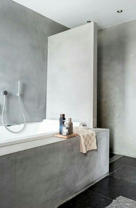 a concrete bathroom with concrete walls and a bathroom clad with concrete and a black tile floor